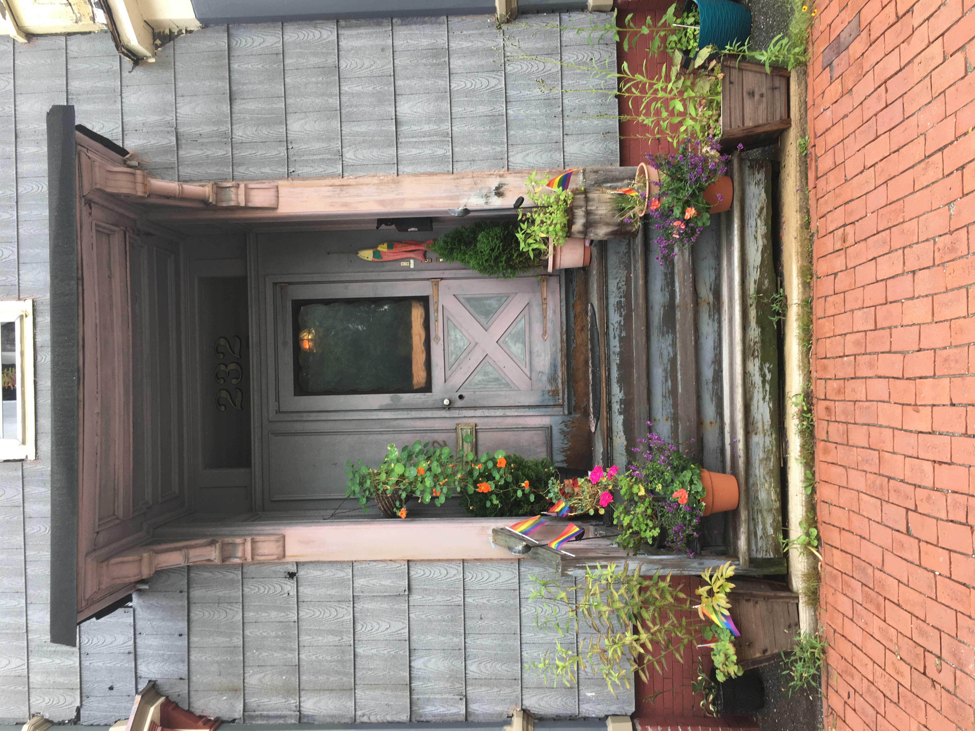 Doorway of 232 Spring Street in Portland Maine with flower pots and rainbow flags on the steps