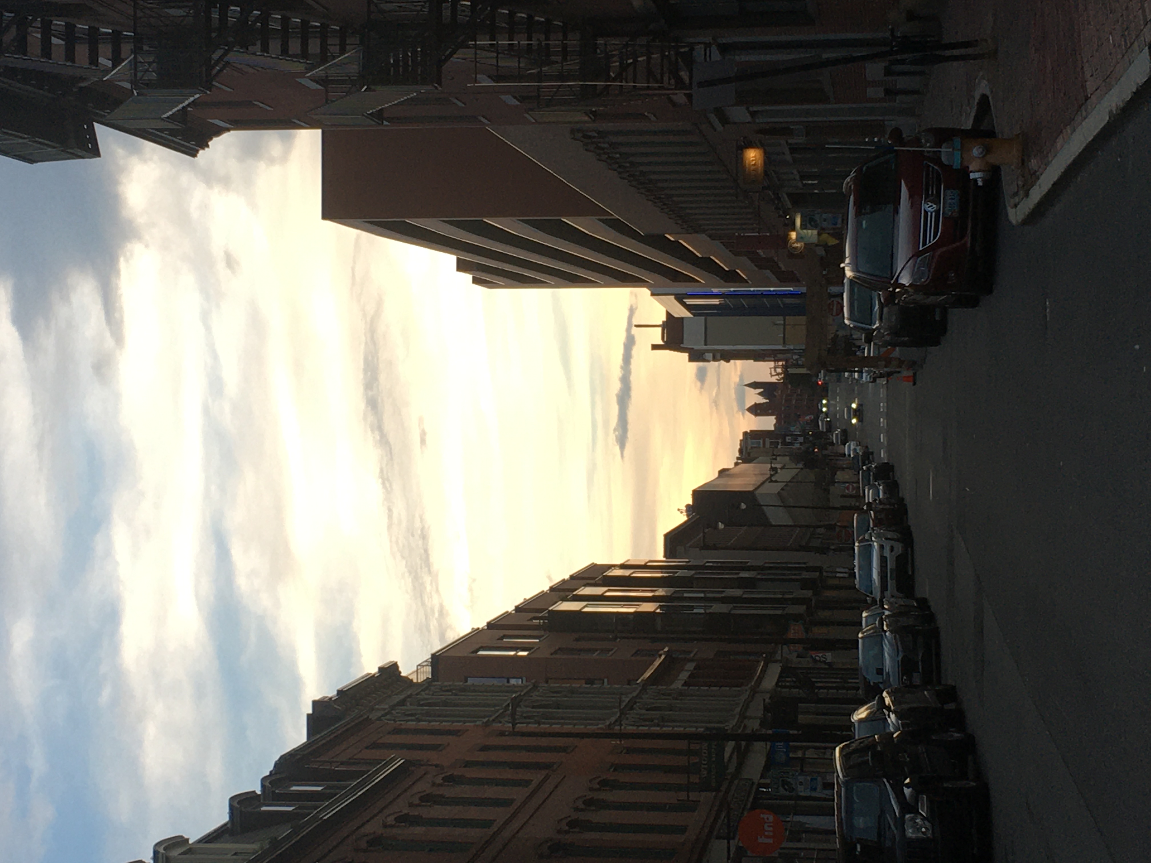 view of street of tall brick buildings with a sunset inbetween