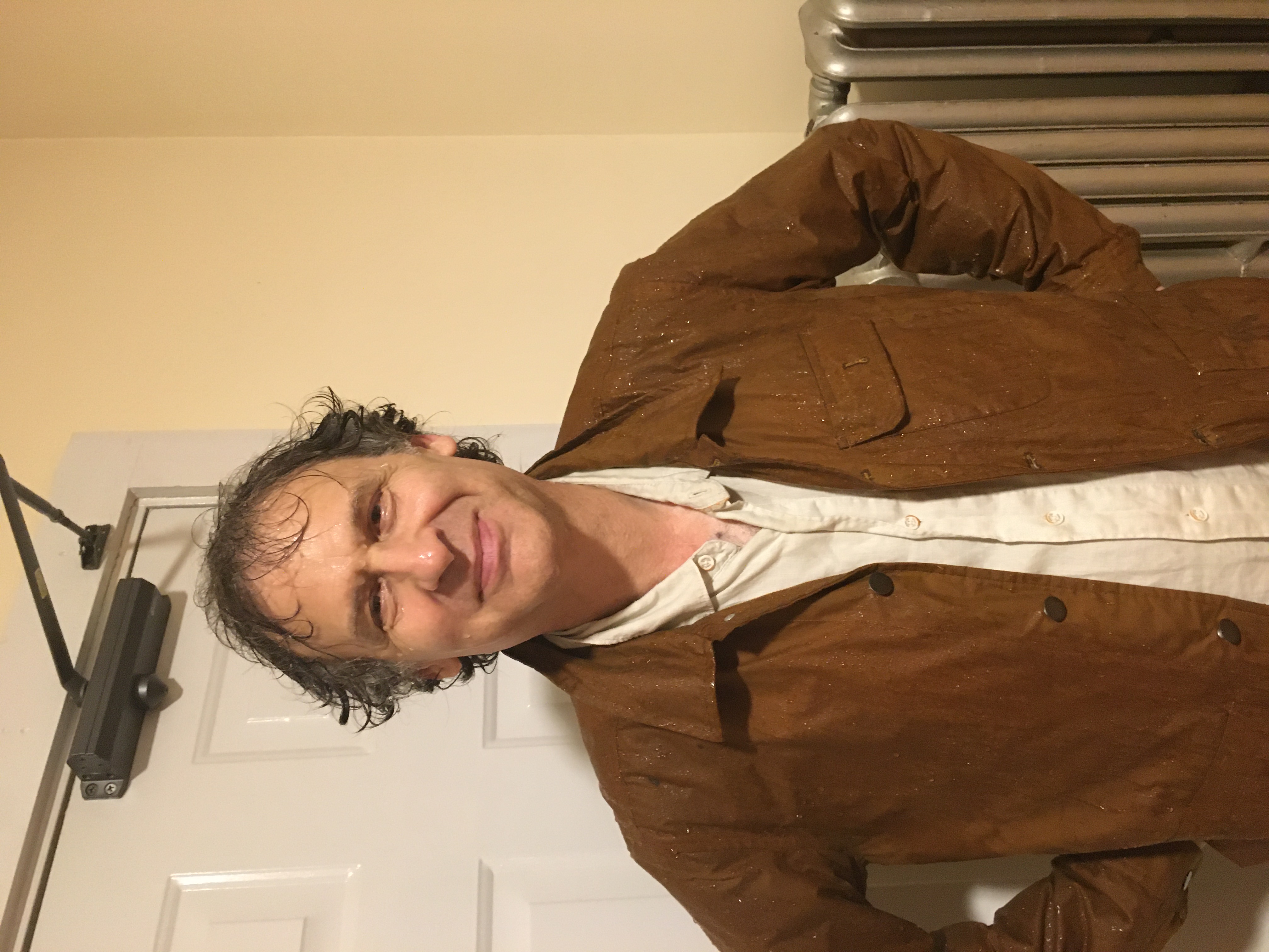 Man with friendly scowl with wet hair and rain running down his face