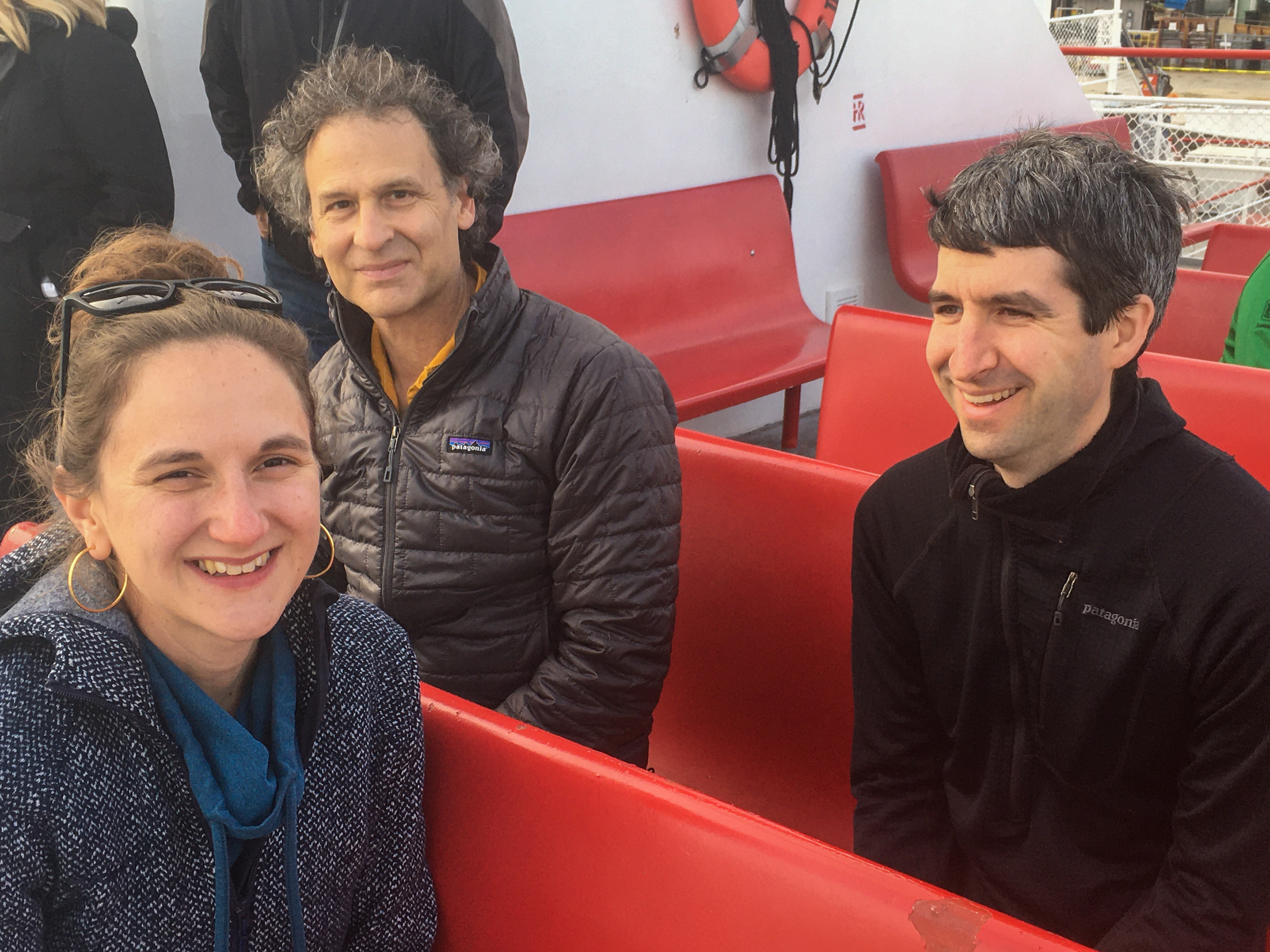 two men and a woman on red bench seats