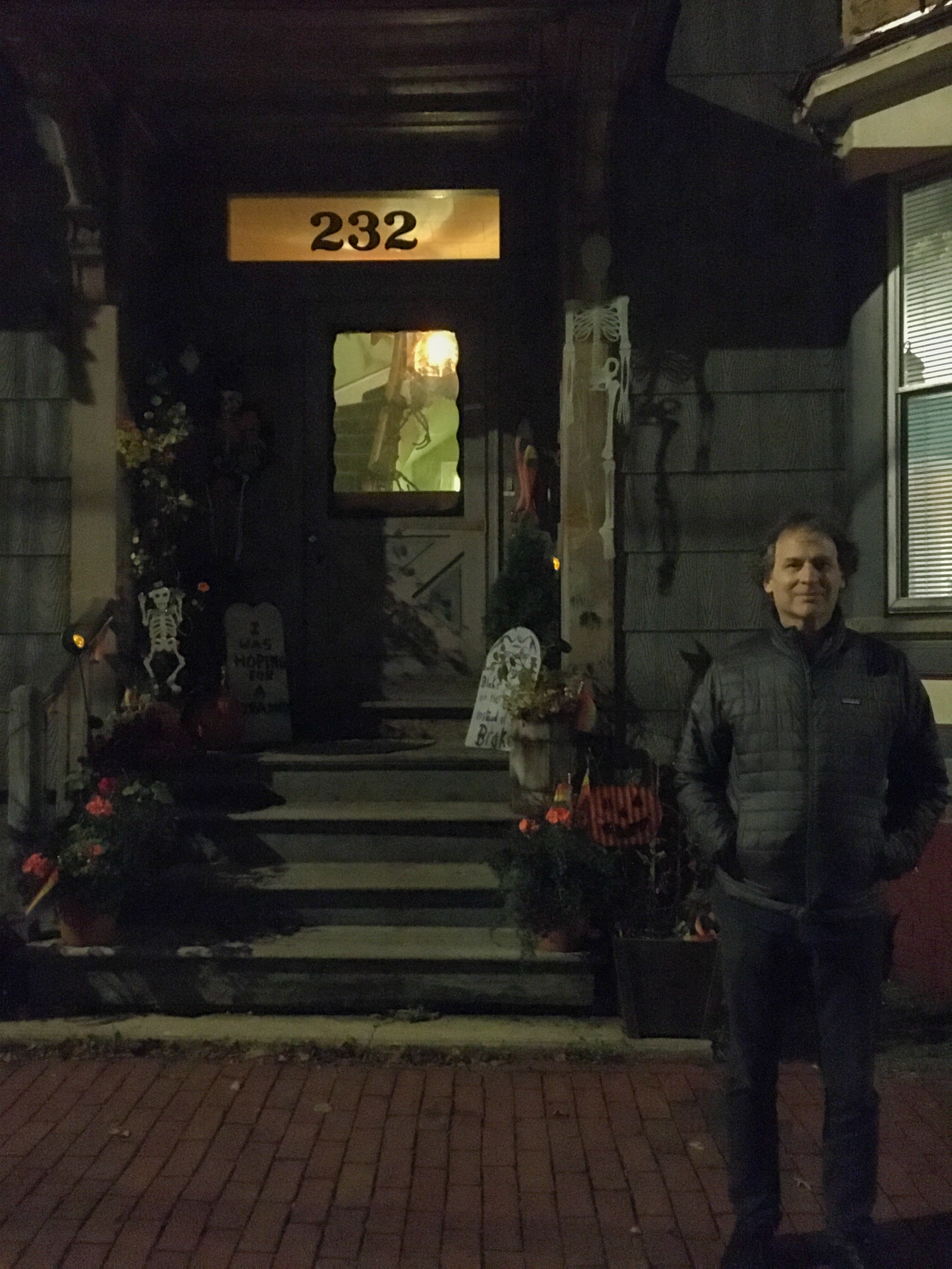 man standing in front of a house with halloween decorations
