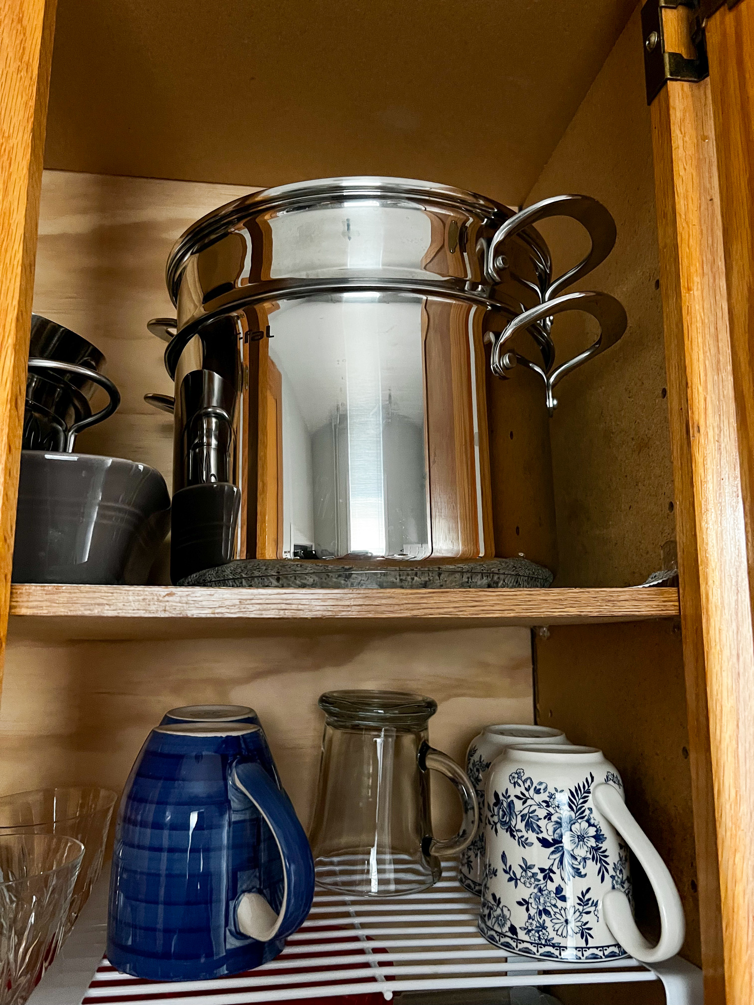 a cupboard with glasses and a large silver pot