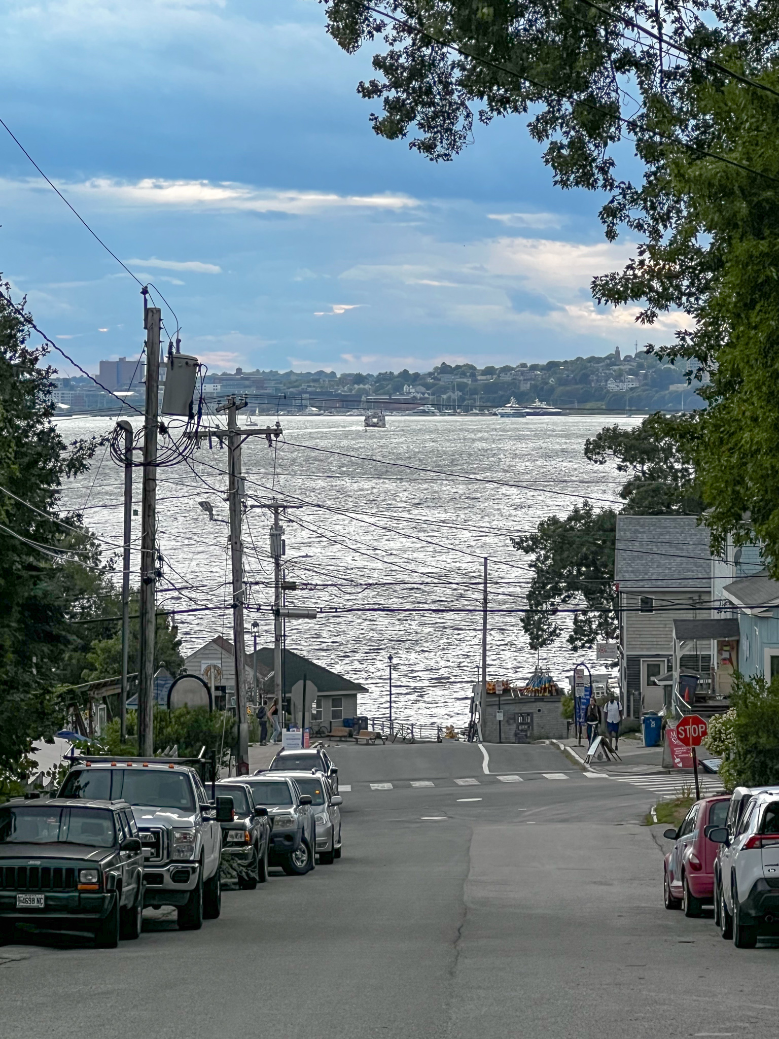 view down a street looking at a body of water with a city across from the water