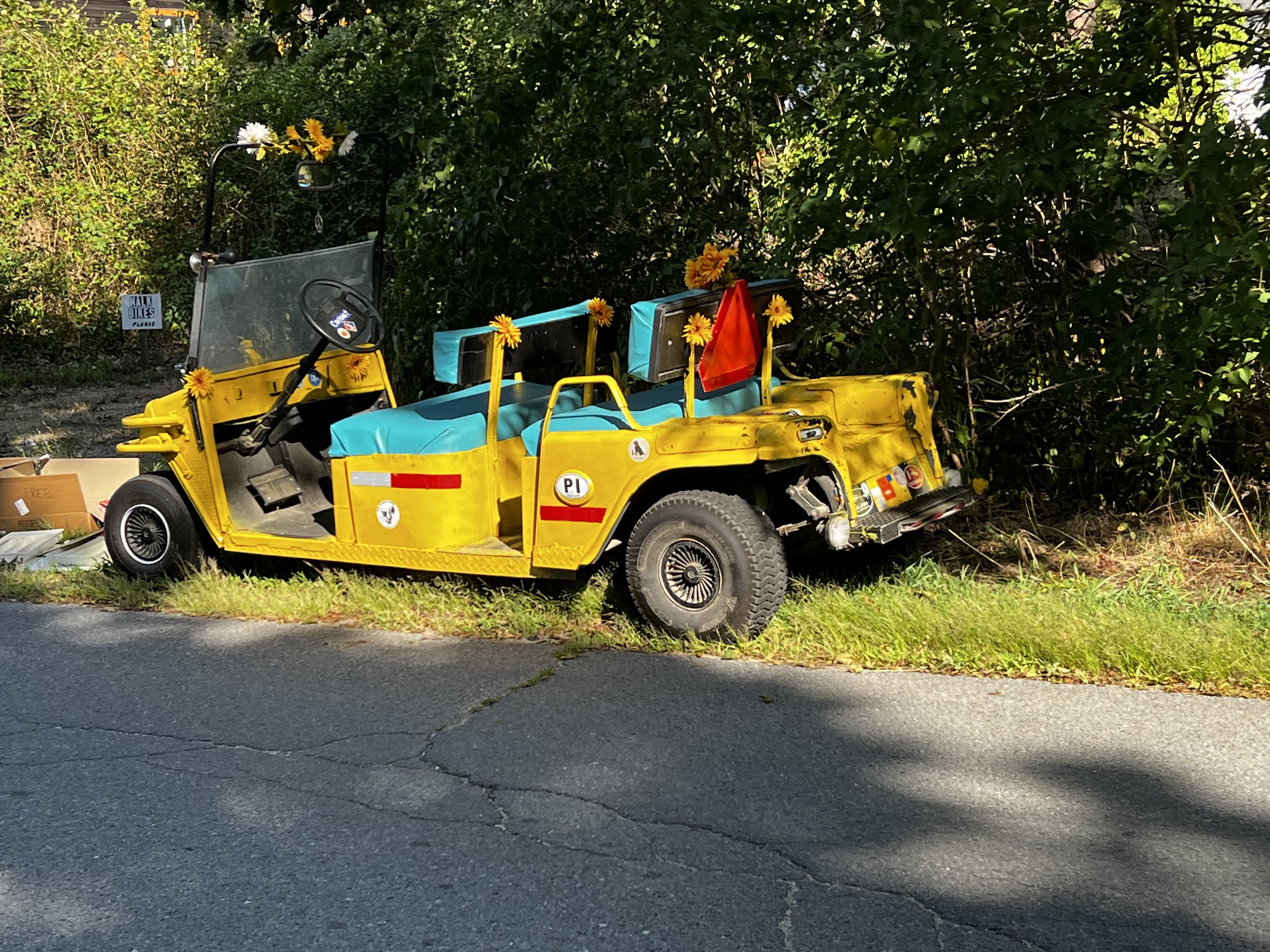 Yellow golf cart with teal seats and red elements covered with sunflowers