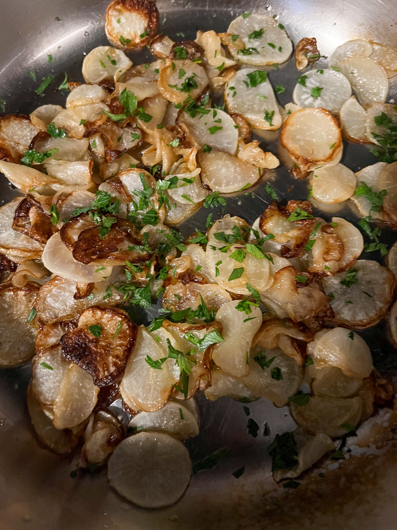 small white japanese turnips sliced thinly and sauteed in a pan with parsley