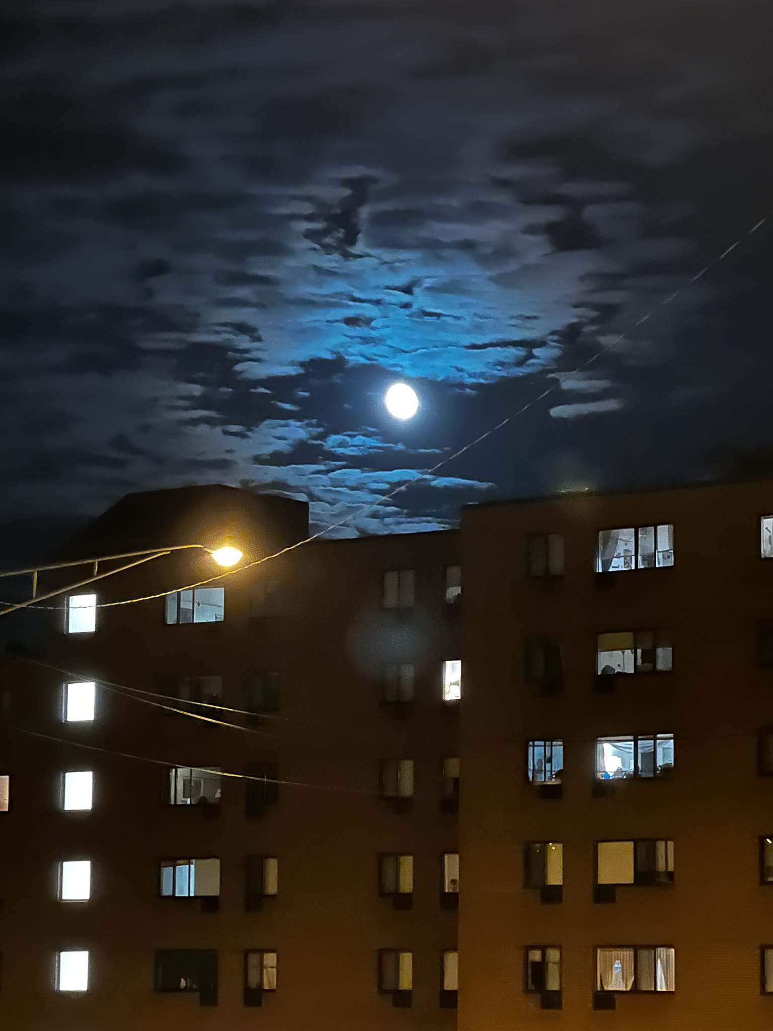 moon over buildings with lots of lighted windows