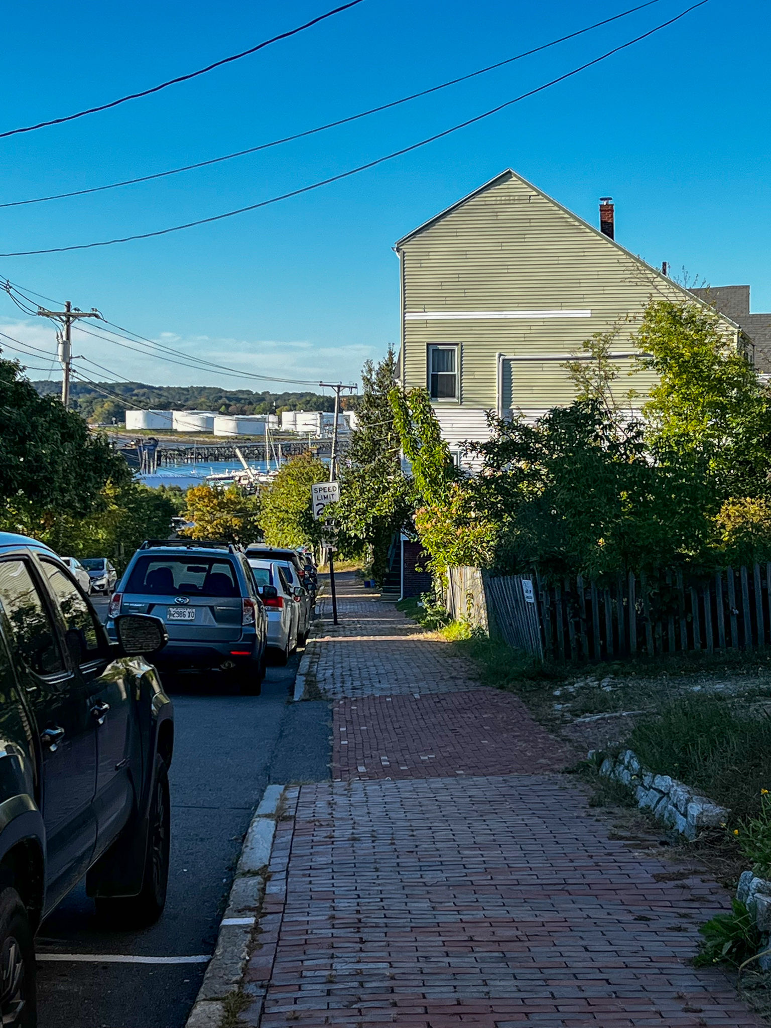 looking down a street and across a body of water at oil tanks