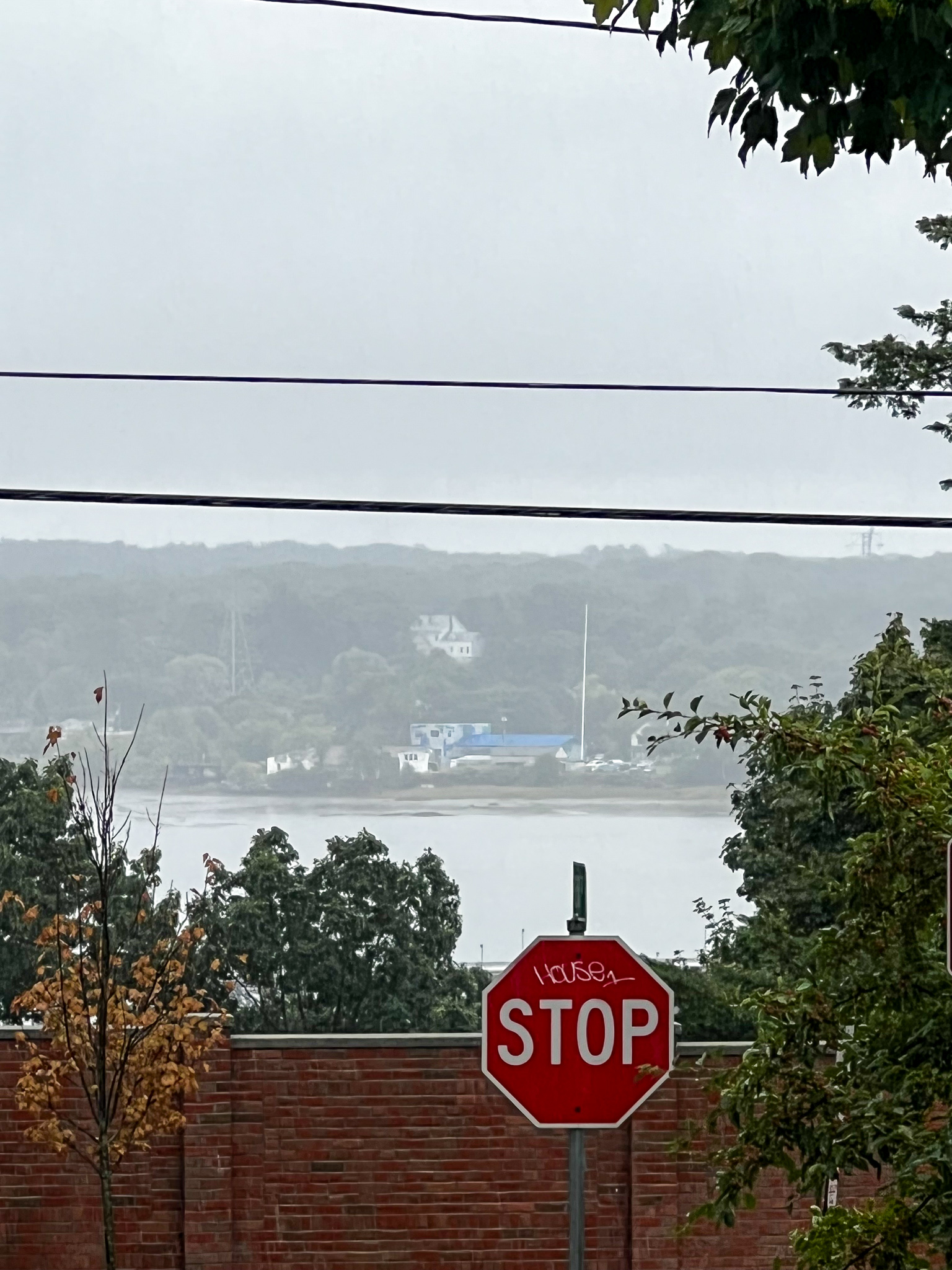 View of a stop sign a brick wall overlooking the Fore River with South Portland beyond