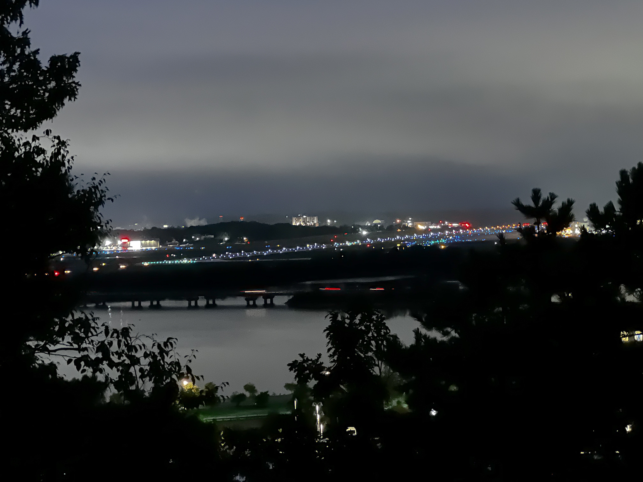 Dusk looking at a body of water and land across with a cloudy sky