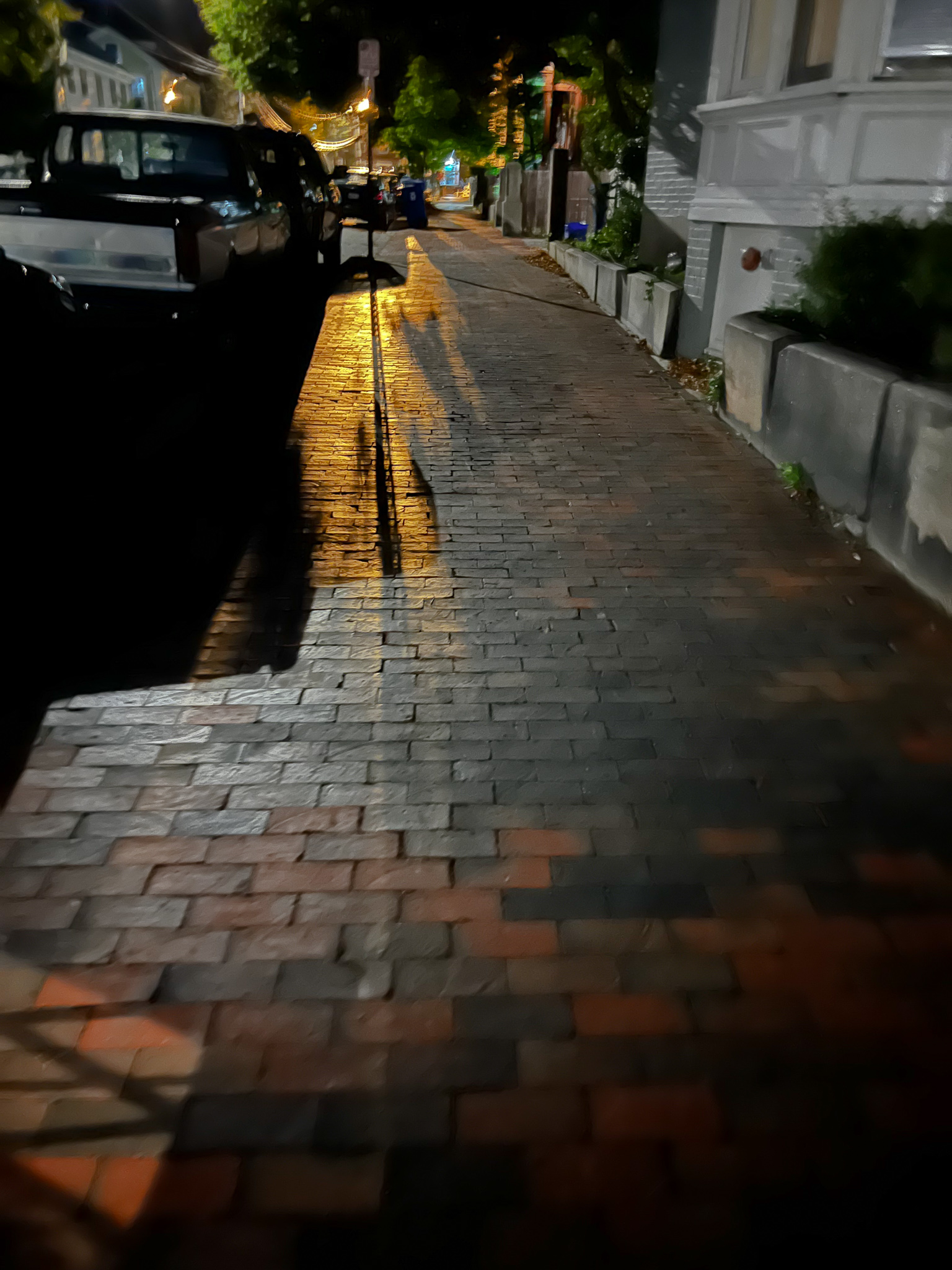 yellow light streaming down a brick sidewalk at night