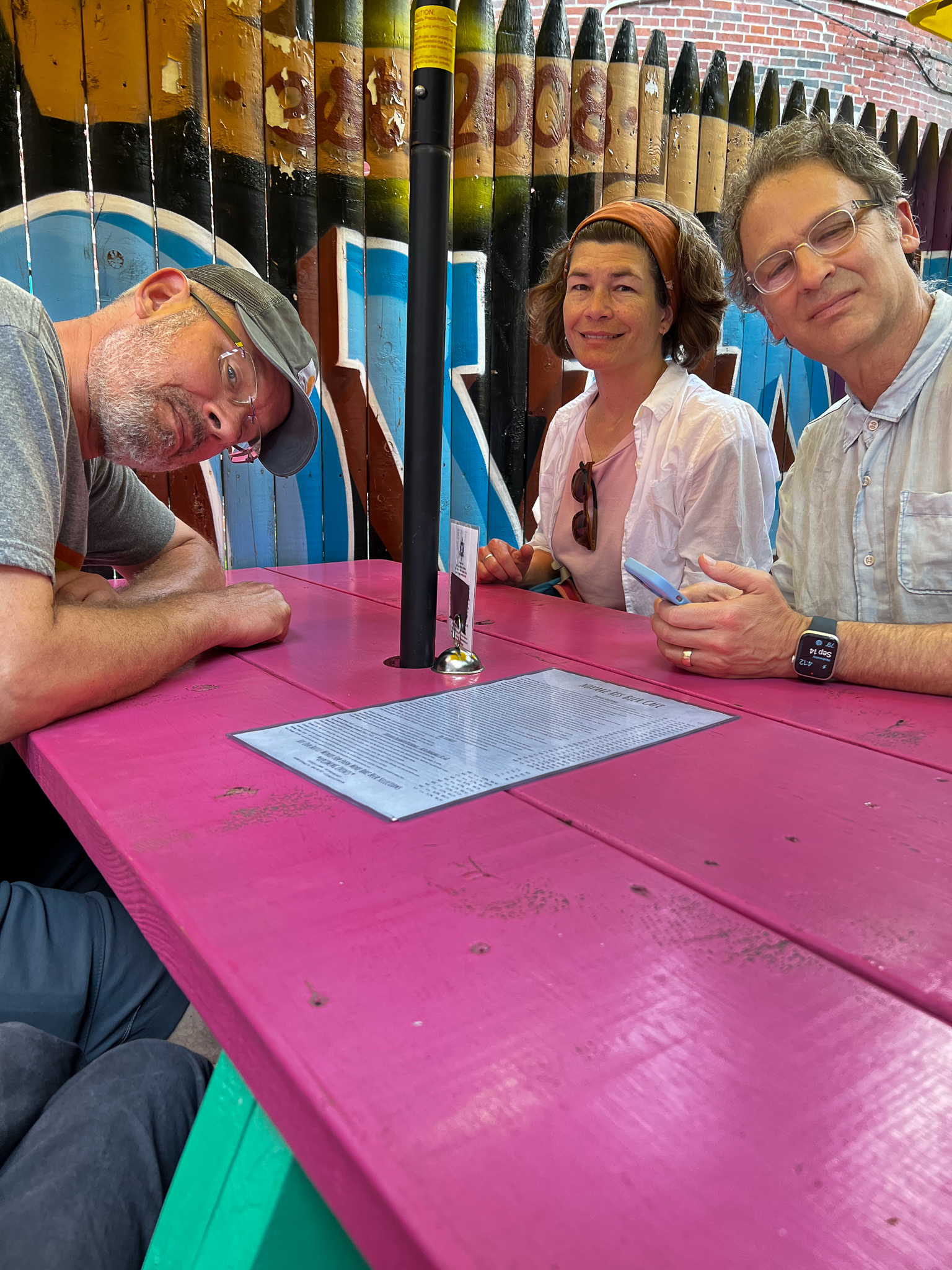 two men and a woman at a bright pink table