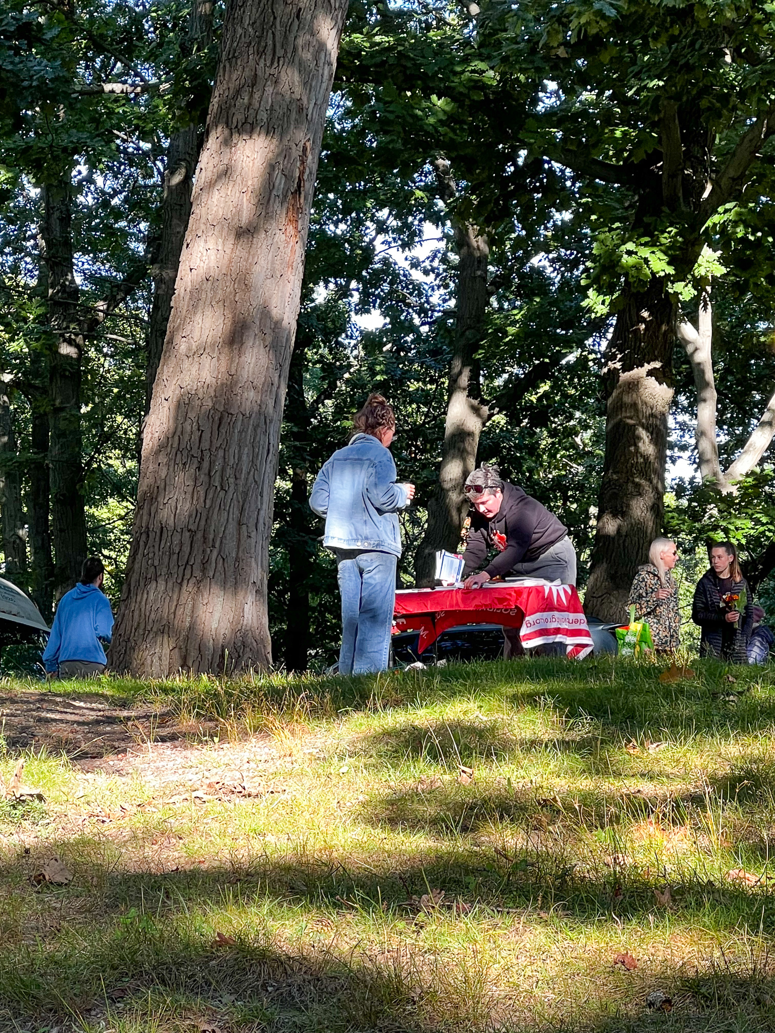 people standing by a table with a red cloth