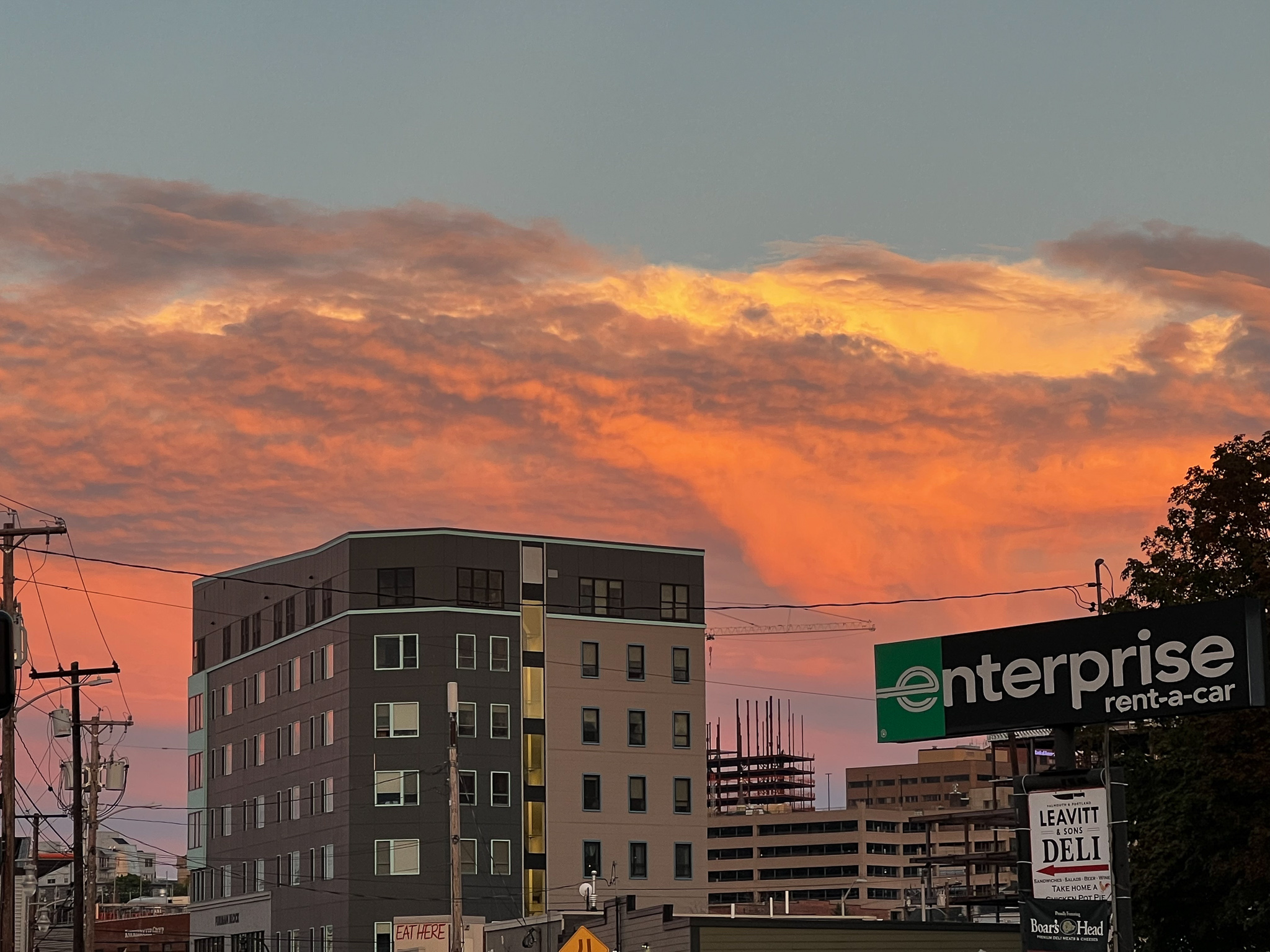 large wall of clouds lit up with sunset and an enterprise sign in the foreground
