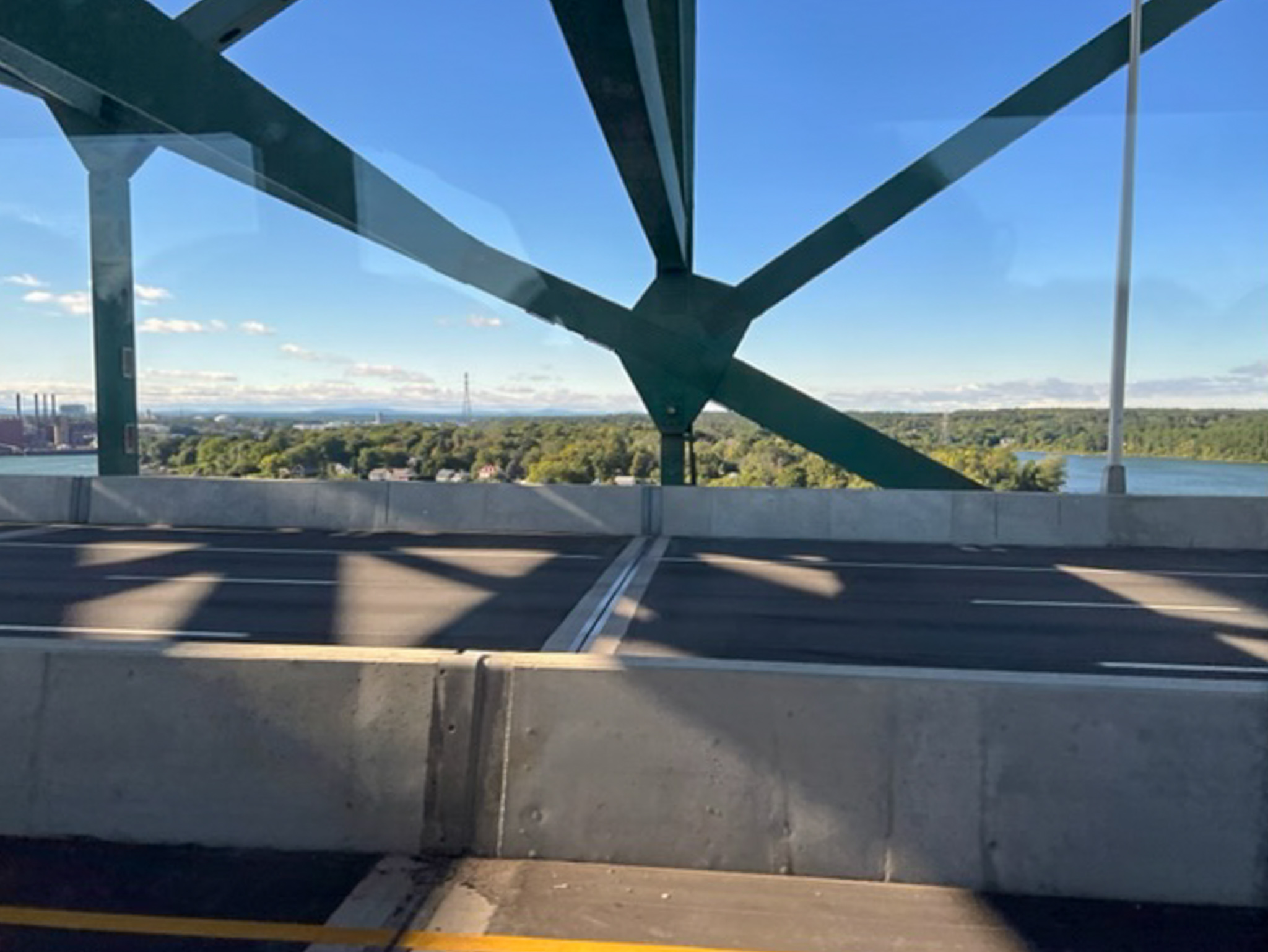 photo of a geometric shape of a bridge looking out the window of a moving vehicle on the bridge