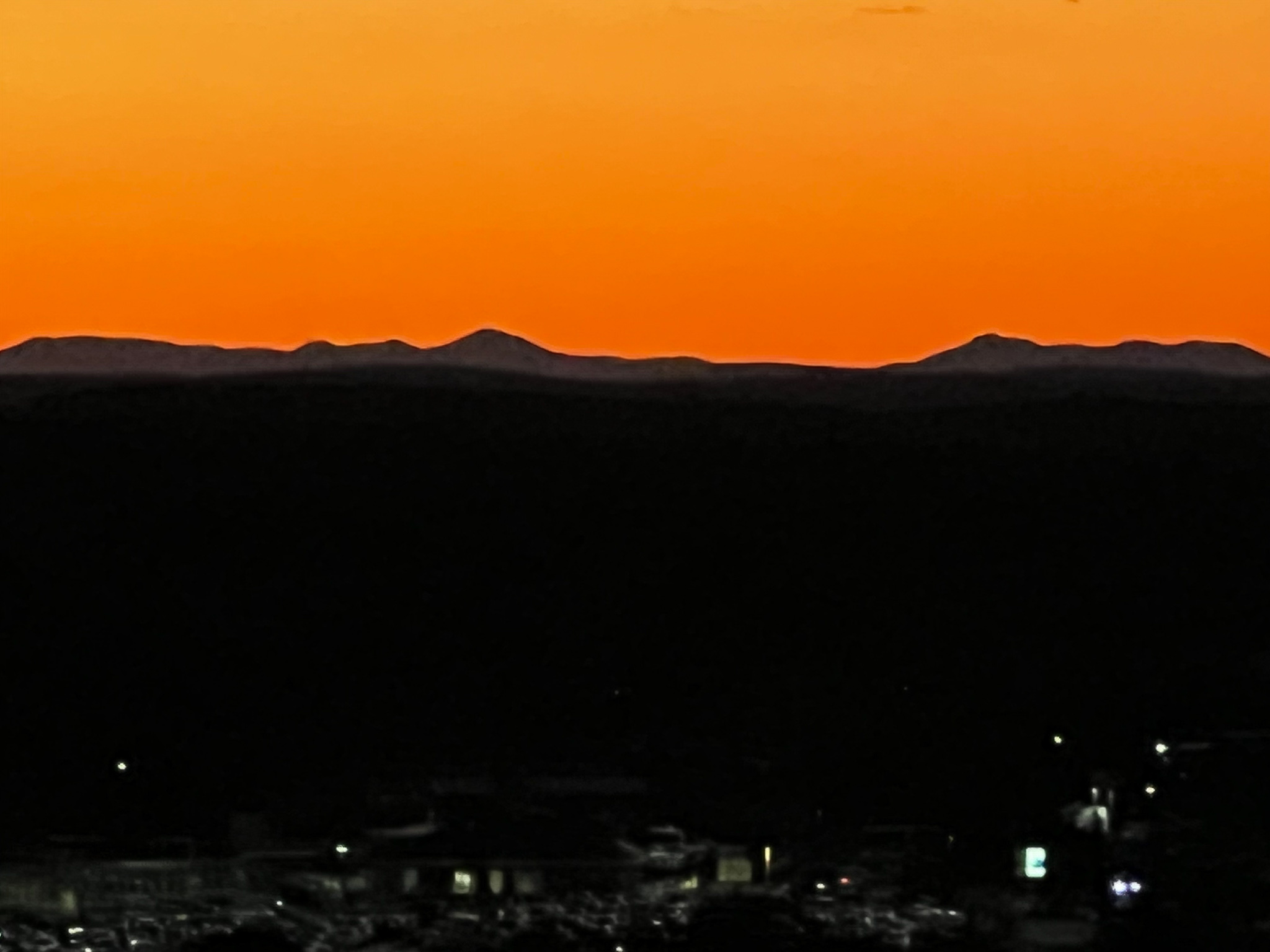 orange sky with mountains in gray and a black landscape below