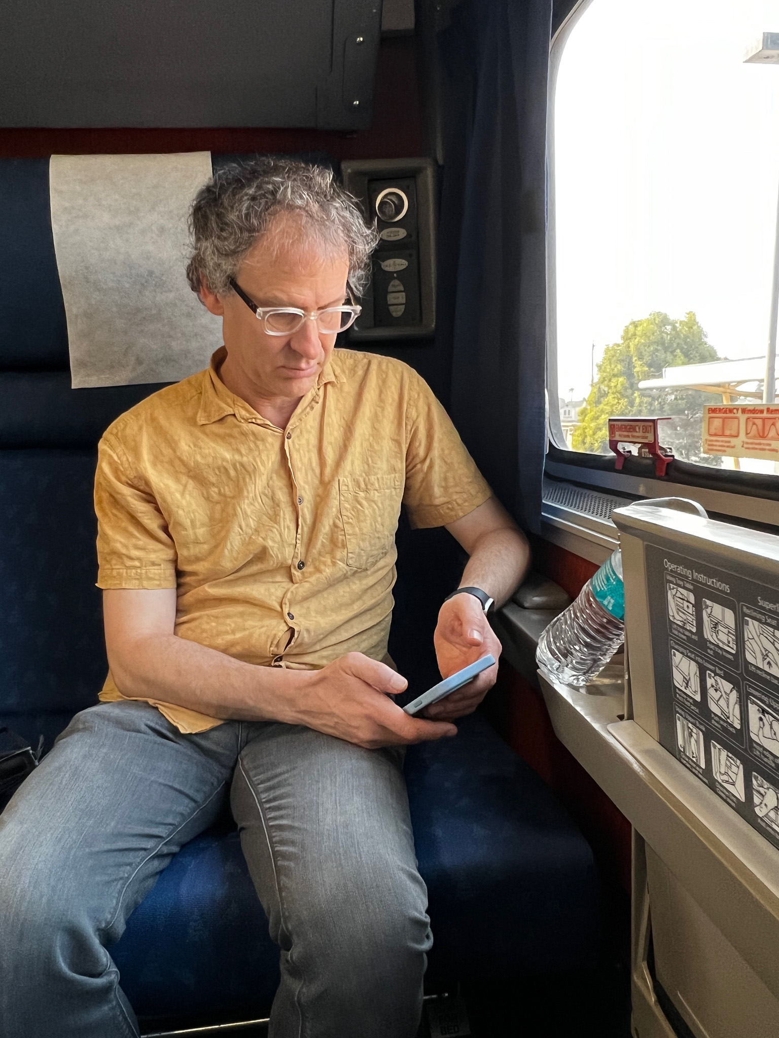 man on a train looking at a mobile
