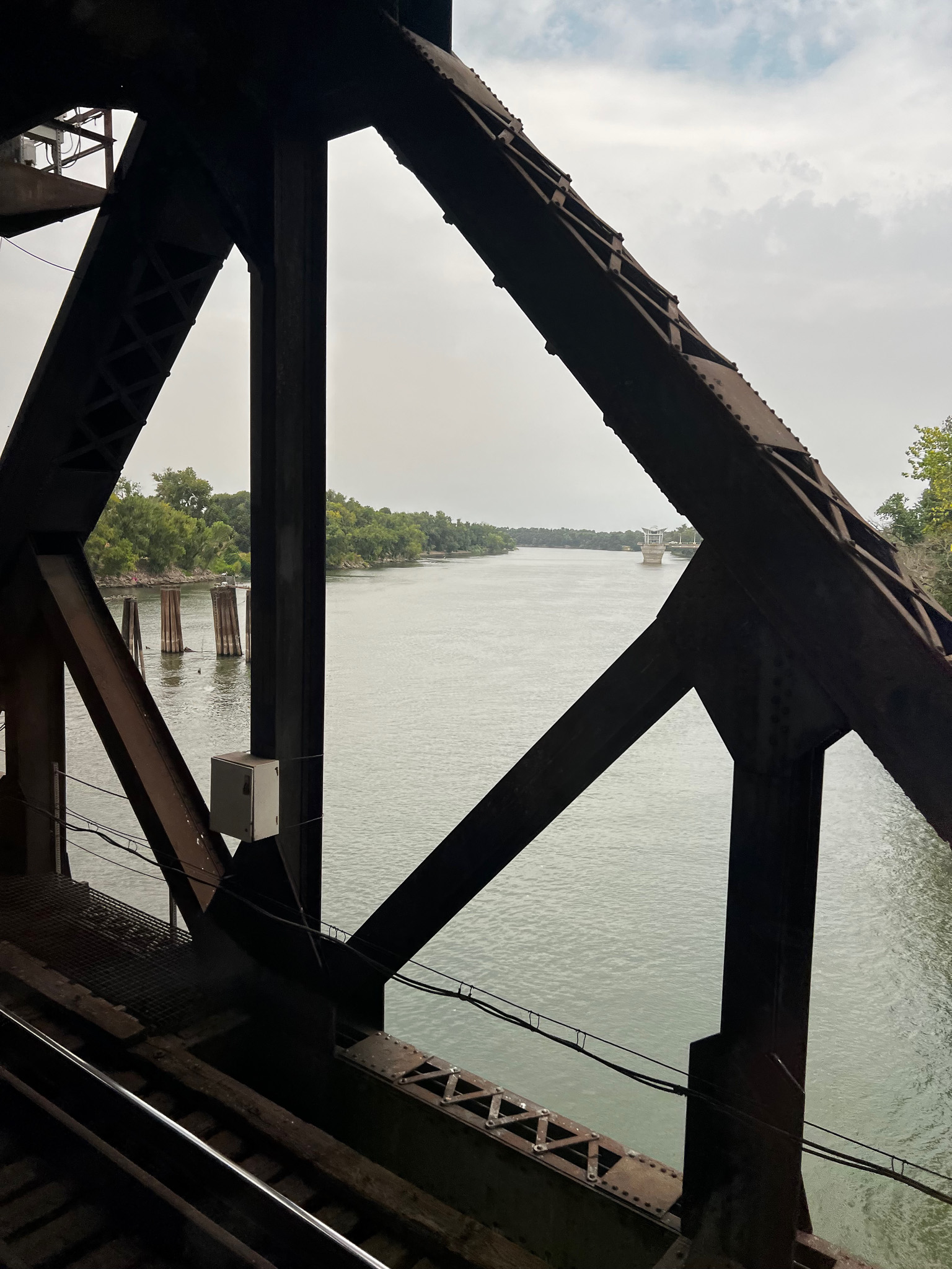 view through a railroad bridge to a still Sacramento river